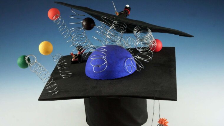 Von Forschungsteam gebastelter Promotionshut, auf dem bunte Molekülkugeln an Sprungfedern auf dem Hut befestigt sind.