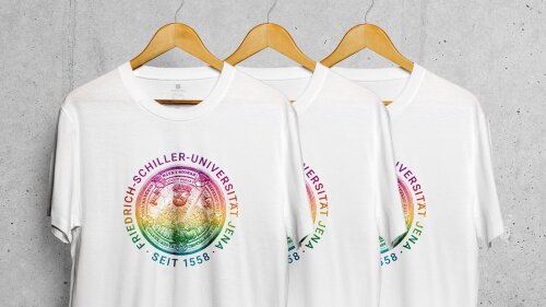 mehrere T-shirts mit "Siegel"-Motiv in Regenbogenfarben hängen hintereinander