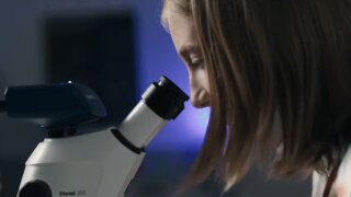placeholder image — Ein Mädchen schaut durch ein Mikroskop.