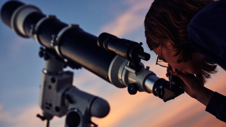 Studentin schaut durch ein Teleskop