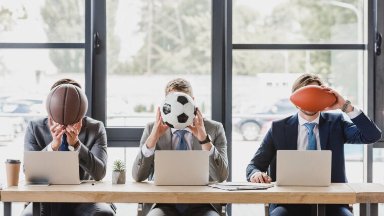 Three men each hold a different sports ball