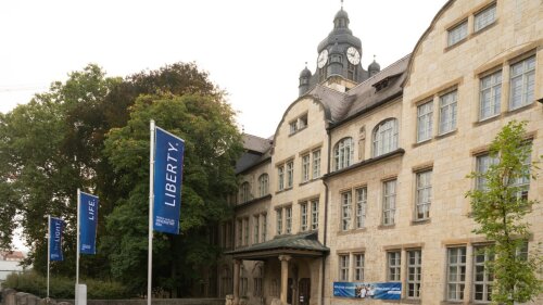 Flags with the slogan "Light, Life, Liberty" fly at the main building of the Friedrich Schiller University Jena.