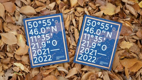 Zwei Ausgaben des Jahresberichts 2021/22 der Uni Jena liegen im Herbstlaub.