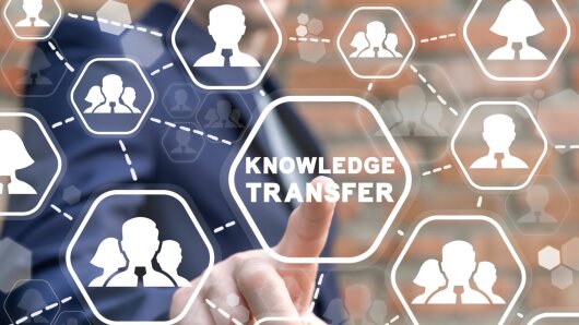 A finger taps on the "Knowledge Transfer" icon, which is surrounded by a network of person icons.