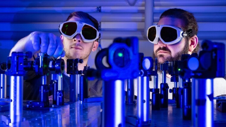 Die Doktoranden Paul Herrmann (l.) und Sebastian Klimmer an einem Laser-Versuchsaufbau.