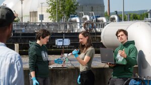 Young researchers analyse a water sample in front of one of the water basins at the central sewage treatment plant in Jena-Zwätzen.