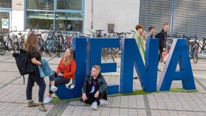 Students next to the letters Jena on the Abbe Campus.