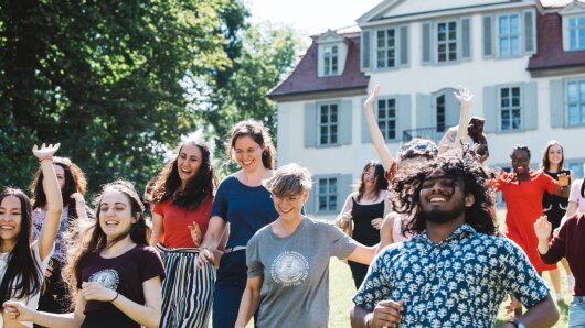 Ein Pulk Studierende läuft lachend bei Sonnenschein die Prinzessinnenwiese hinunter