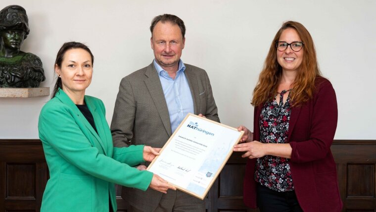 Franziska Neugebauer (l.) von der IHK Ostthüringen zu Gera überreicht an Präsident Andreas Marx (m.) und Claudia Hilbert (r.) vom Green Office die Urkunde zur Teilnahme am NAThüringen.