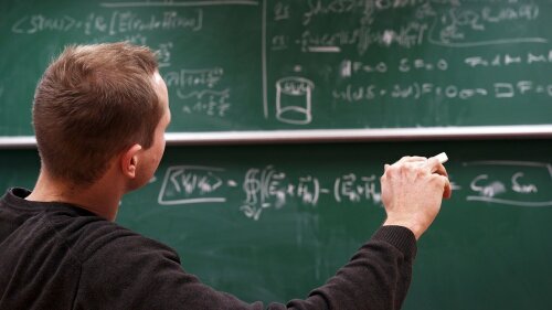 Postdoc in front of blackboard with formulas